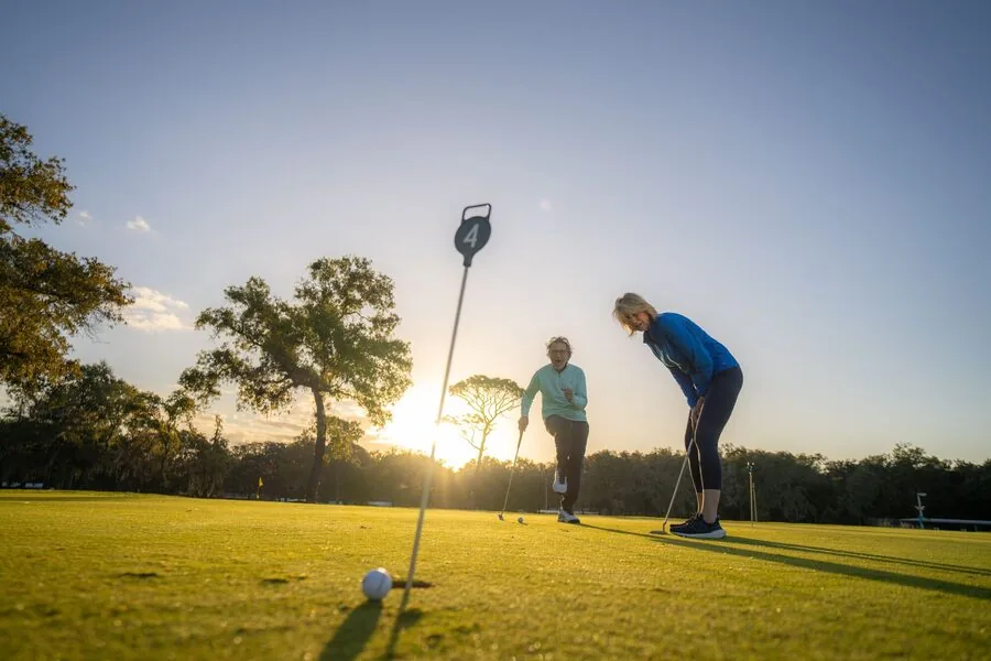 A couple putting at golden hour, Rolling Greens Village